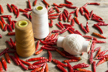 Red pepper and sewing thread on the tableの写真素材