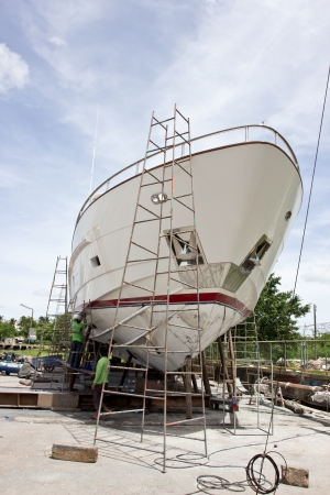 Phuket,Thailand, June 11, 2013 Boat repair yard worker inspecting a wooden boat for repair のeditorial素材