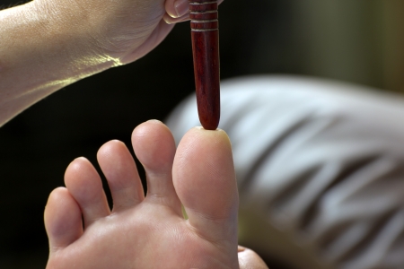 foot massage by wood stick for frontal sinuses  の写真素材