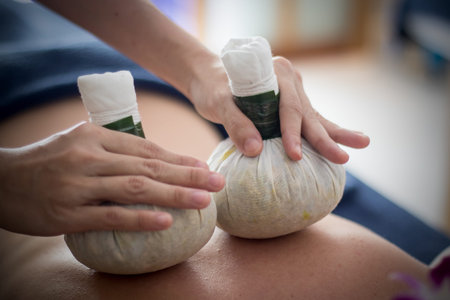 woman getting thai herbal compress massage in spaの写真素材