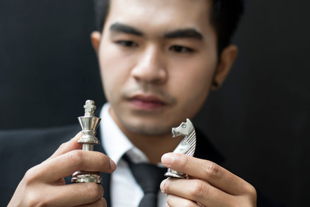 concept of young business man looking at  chess on his hand and planning business planの写真素材