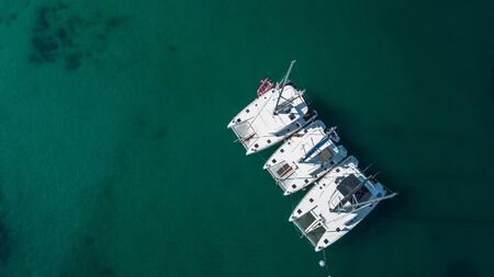The drone captures a high angle view of catamaran sailboats moored in the Andaman sea.の写真素材