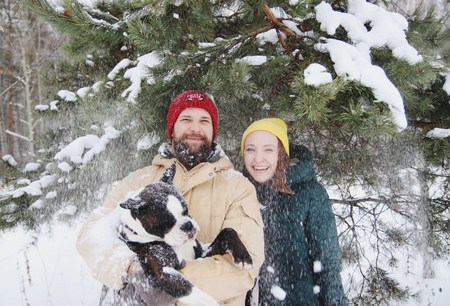 Happy couple in love having fun in the snow with his baby dogの写真素材