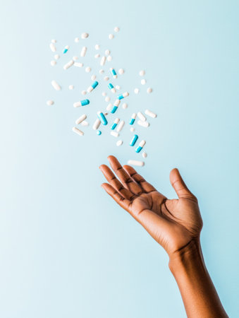 Hand reaching out floating towards blue and white pills on a light blue background, AI generatedの素材