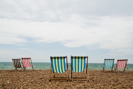 6 stripy deck chairs on a shingle beach in Brighton, Southwest England  Taken on an overcast dayの写真素材