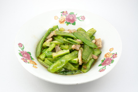 Stir fried snow peas and pork on plate with white backgroundの写真素材