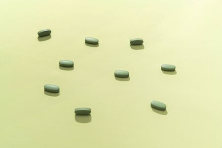 Flat lay composition of green pills on green background.の写真素材