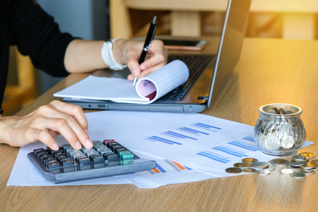 Close up of yong asian female business owner making calculations. Savings, finances and economy conceptの写真素材