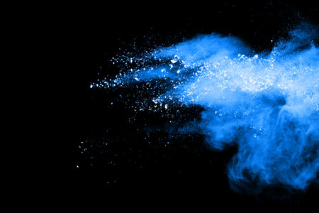 Blue dust explosion on black background. Freeze motion of color powder splash.の写真素材