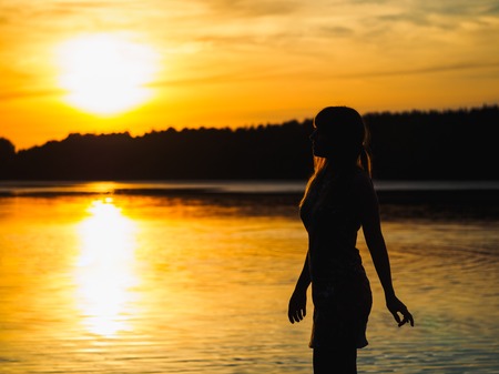 Silhouette of a girl on the bridge by the riverの写真素材