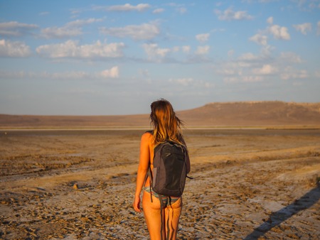 A girl in a swimsuit is walking at sunset over salt lakeの写真素材