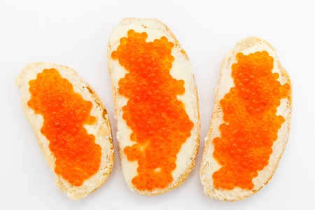 Three white bread sandwiches with butter and red caviar on a white background.の写真素材