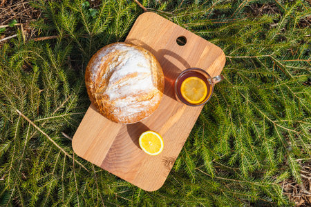 Fresh white bread on a cutting board and red tea with lemon. Against the background of green...