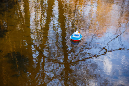 Toy ship sailing in the river at sunset.