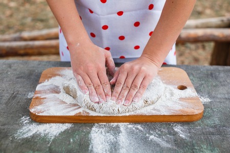 Women's hands knead the dough of dark rye flour.の写真素材