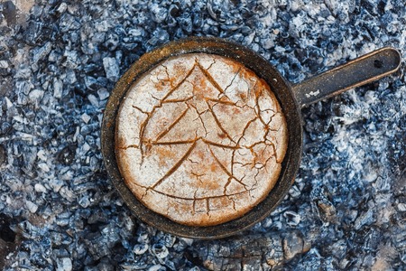 Cooking bread on fire coals in the evening.の写真素材