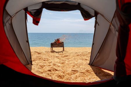View from the tent to the sea. In the background is a burning barbecue.の写真素材