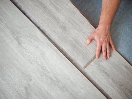 A man holds a laminate board in his hands. The repair process in the room.