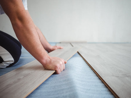 The repair process in the apartment. Man laying laminate flooring.