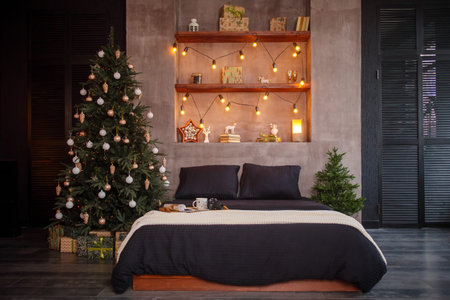 Christmas room interior made of bed and Christmas tree with garlands.