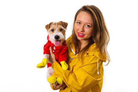 Portrait of a smiling girl in a yellow raincoat with a dog Jack Russell Terrier in a red jacket in...