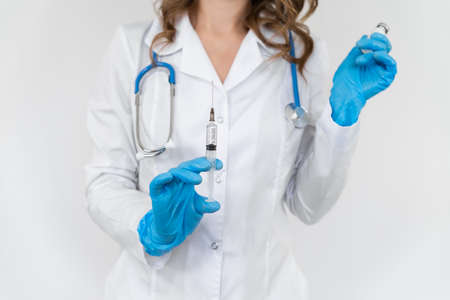 Portrait of a doctor in a bathrobe with a stethoscope. The girl holds a medical syringe in her hands. isolated on white background.の写真素材