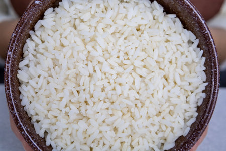 Brown plate with golden rice in the hands of a girl close-up. Asian food concept.の写真素材