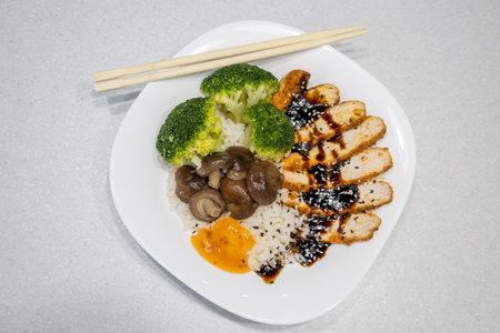 Plate with golden rice, shiitake mushrooms, chicken with unagi sauce and broccoli. The dish is garnished with black and white sesame seeds. Asian food conceptの写真素材