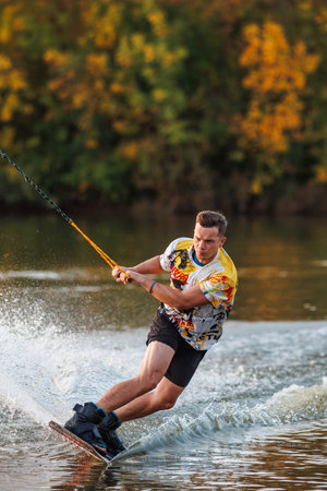 An athlete performs a trick on the water. Park at sunset. Wakeboard rider.の写真素材