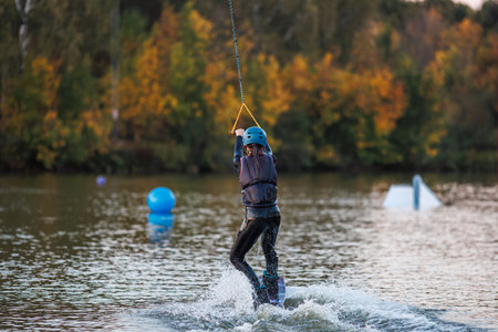 Girl on a wakeboard. An athlete performs a trick on the water. Autumn Park.の写真素材