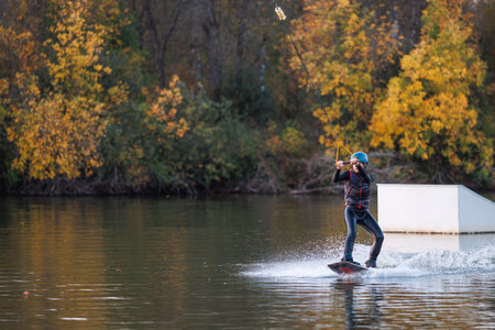 Girl on a wakeboard. An athlete performs a trick on the water. Autumn Park.の写真素材