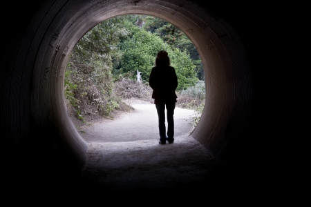 A woman walks from a dark tunnel into the light of dayの写真素材