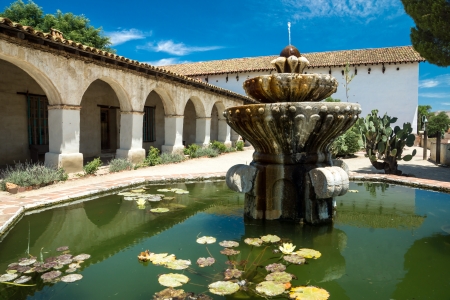 Fountain with lily pads beside a colonnade at an historic  California missionの写真素材