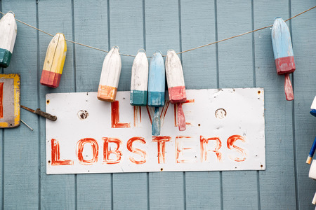 Buoys hang above a faded sign promoting lostersの写真素材