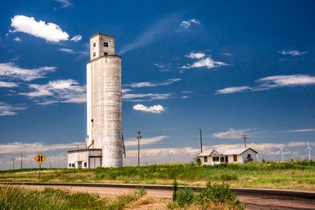 An old grain silo stands above a texas wind farm, contrasting the old and new economy.