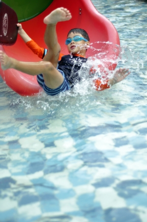 Kid having fun sliding down at swimming pool.の素材