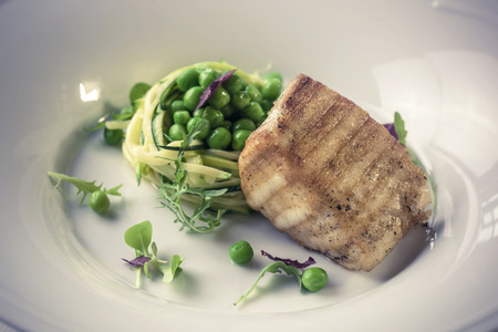 Grilled Butter fish steak with zucchini-pea stew braised in white wineの写真素材