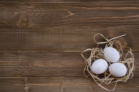 Easter white eggs in nest on wooden backgroundの写真素材
