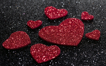 Red Valentine's day hearts with bright white spots on a black glittery backgroundの写真素材