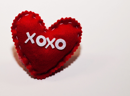 A red handmade cloth heart with "XOXO" written across the front of it. There is space for added text in the shotの写真素材