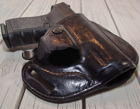 A black 9mm pistol shown in a holster laying on a wooden table