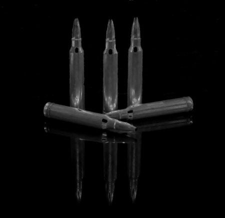 An abstract shot of five subdued rifle bullets with a black backgroundの写真素材