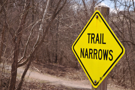 A "Trail Narrows" sign in the woods next to a hiking pathの写真素材