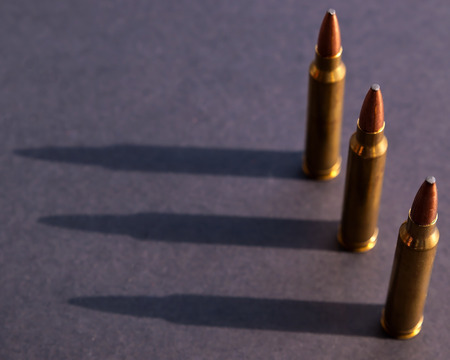 Three high power rifle bullets lined up on a black background with each one casting a shadowの写真素材