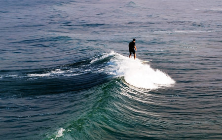 A lone surfer on  riding a wave on a surf board on the Pacific ocean in southern California, USA in...