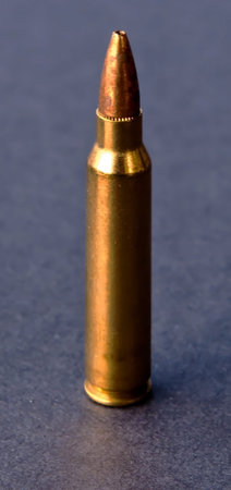 A single .223 caliber hollow point bullet on a black background