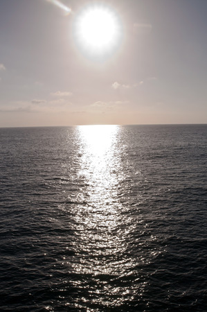 The sun brightly shining with it's reflection over the Pacific ocean off the coast of southern California, USAの写真素材