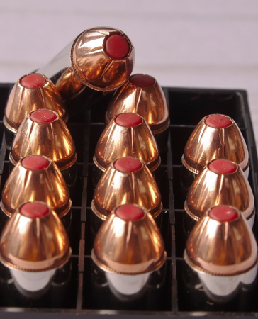 Twelve 44 special bullets with red tips in a black case with one of them on top of the others showing  an open spot in the caseの写真素材
