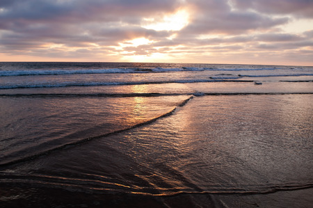 The sun setting over the Pacific ocean seen from a beach in summertime in southern California, USAの写真素材