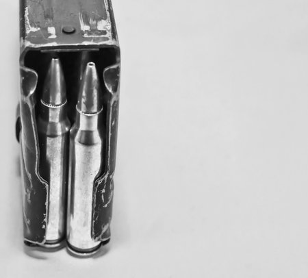 A AR-15 rifle magazine loaded with .223 caliber rifle bullets on a gray background with copy space....